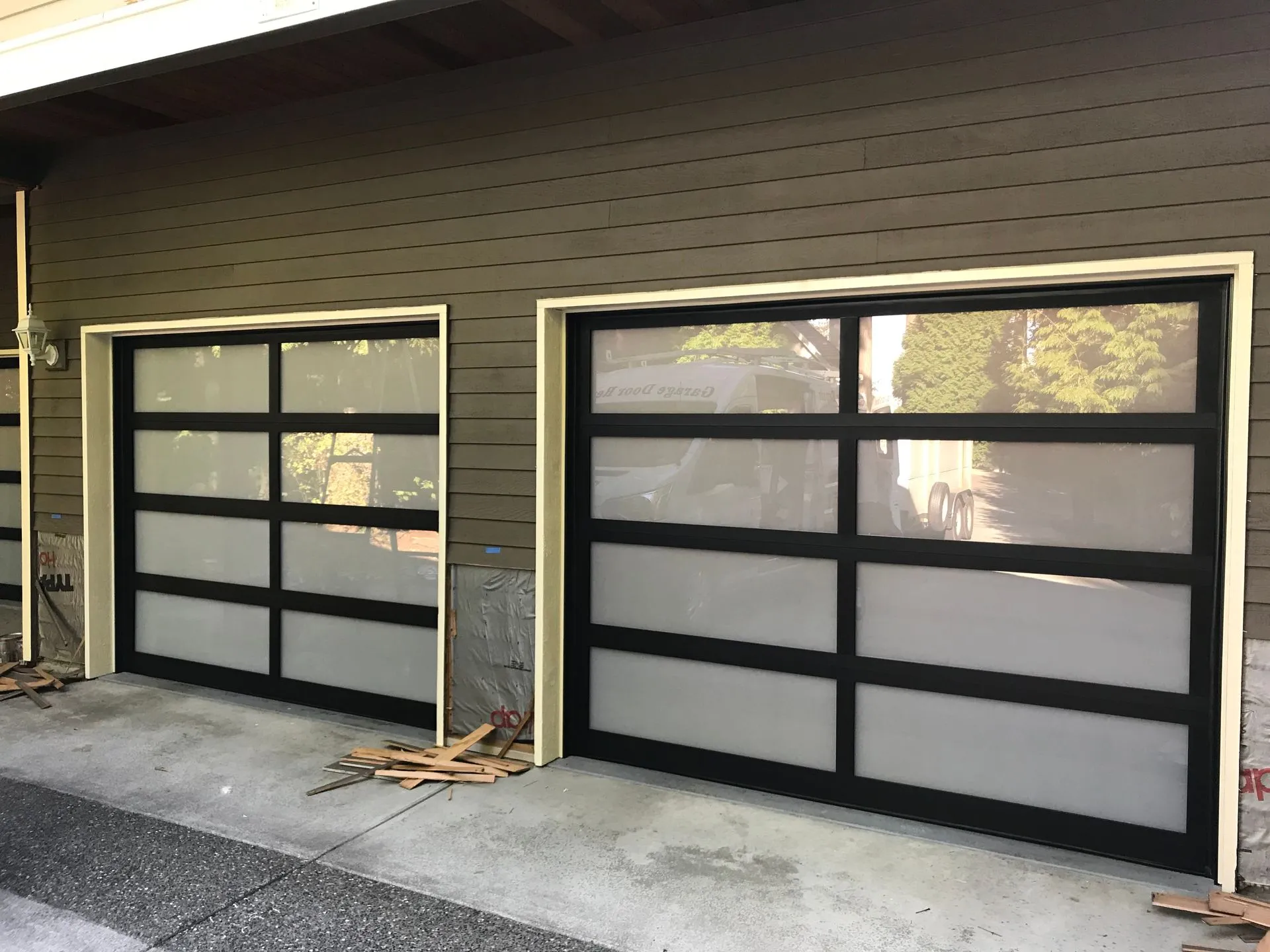 Pair of black-framed Alumadoor full-view glass garage doors on a house