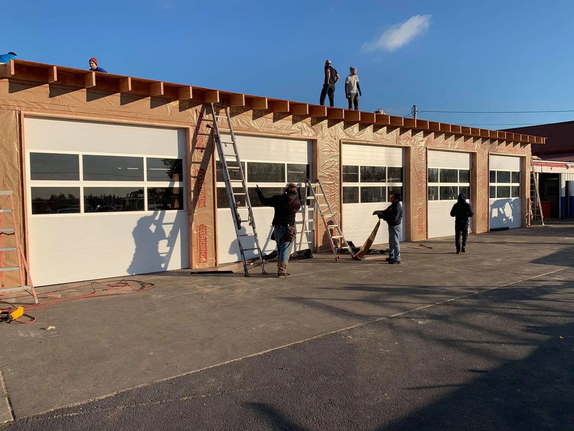 A-1 crew fitting five white commercial sectional doors with window rows on a new building