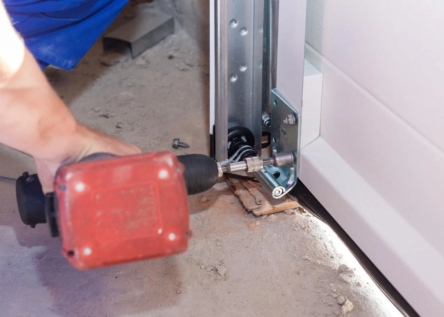 Fitting the bottom bracket and lift cable to a garage door with a power driver