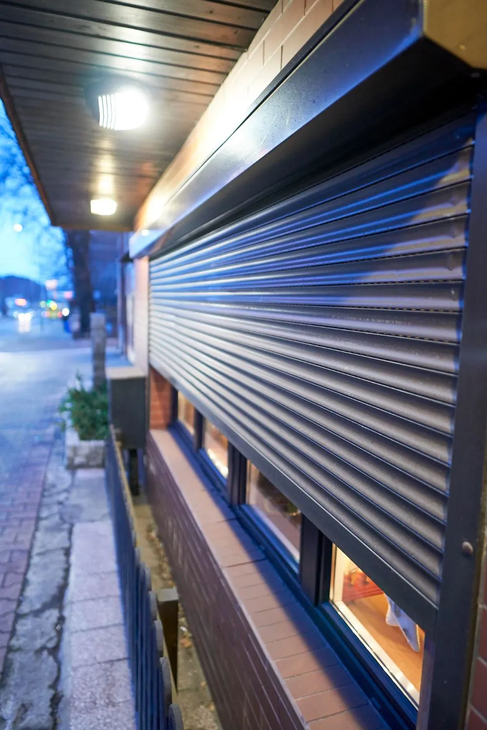 Dark metal roller shutter closed over a shopfront at dusk