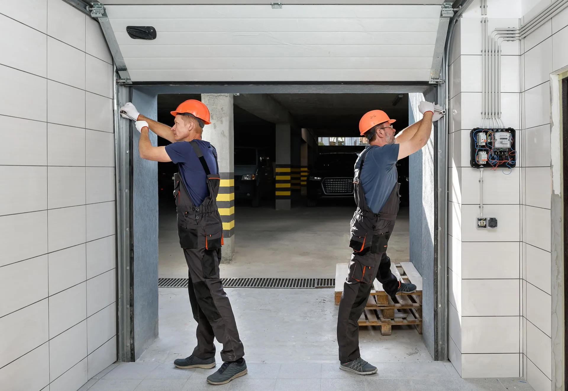 Two technicians tightening the side tracks on a newly fitted sectional door